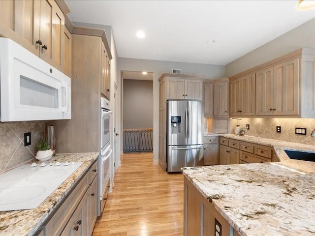 kitchen with visible vents, white appliances, light wood-style floors, and decorative backsplash