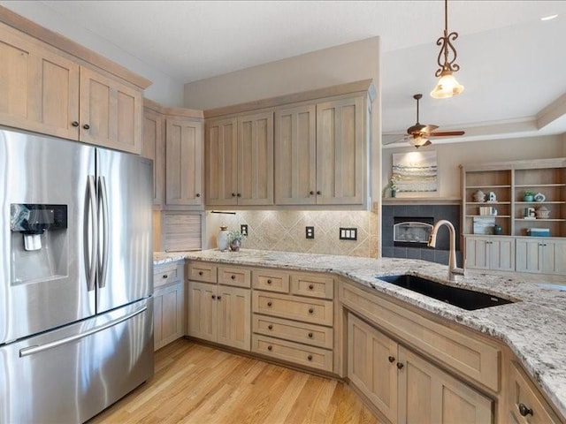 kitchen with light brown cabinets, a ceiling fan, a sink, stainless steel fridge with ice dispenser, and light wood finished floors