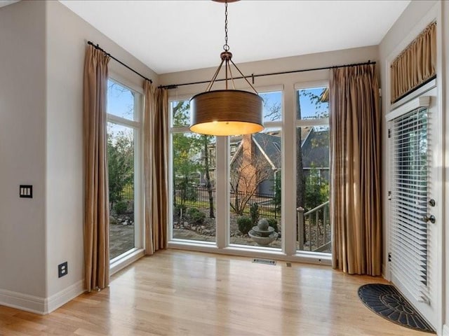 unfurnished dining area with visible vents, light wood-style flooring, and baseboards