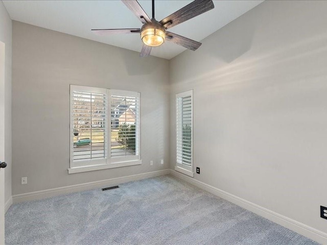 carpeted spare room with visible vents, a ceiling fan, and baseboards