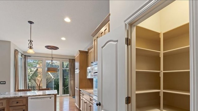 kitchen with light stone countertops, recessed lighting, white dishwasher, light wood-style floors, and decorative light fixtures