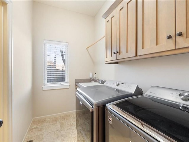 clothes washing area featuring cabinet space, washing machine and dryer, baseboards, and a sink