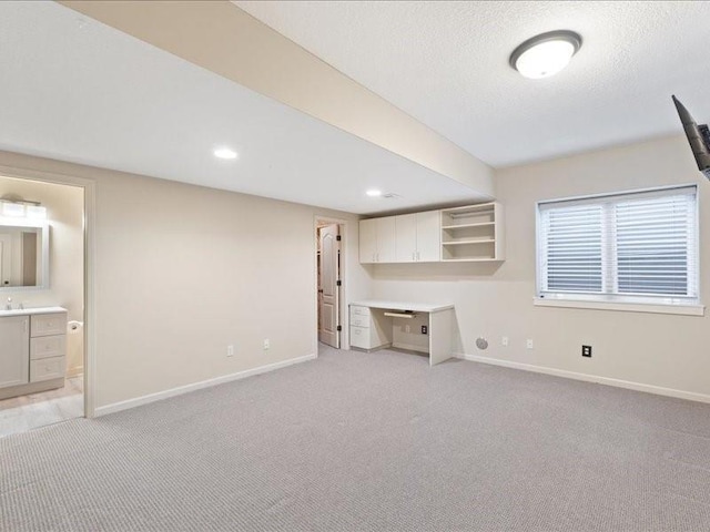 interior space with a textured ceiling, baseboards, and light carpet