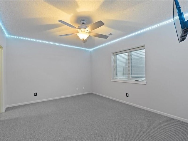 unfurnished room with a textured ceiling, baseboards, carpet floors, and ceiling fan