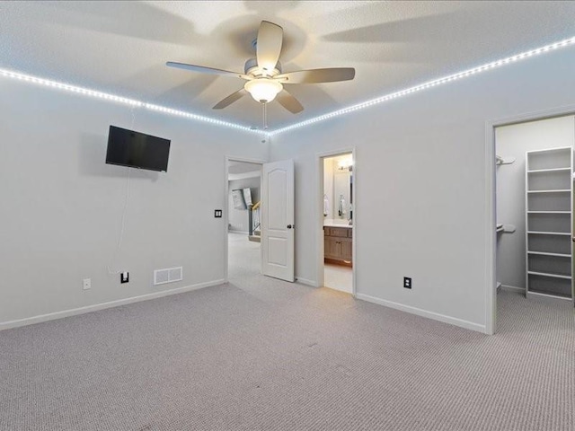 unfurnished bedroom featuring visible vents, light colored carpet, and a walk in closet