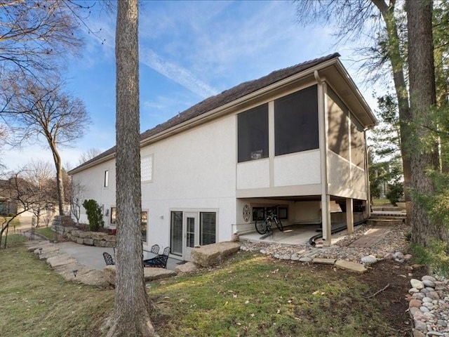 rear view of house featuring a patio area, stucco siding, and a sunroom