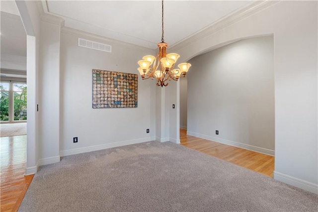 empty room featuring visible vents, carpet floors, arched walkways, ornamental molding, and a notable chandelier