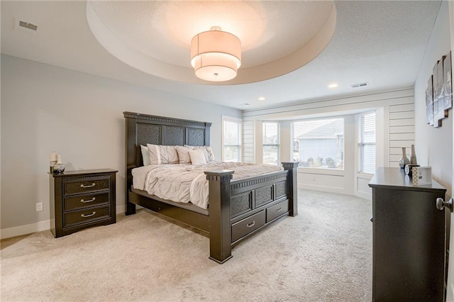 carpeted bedroom with a tray ceiling