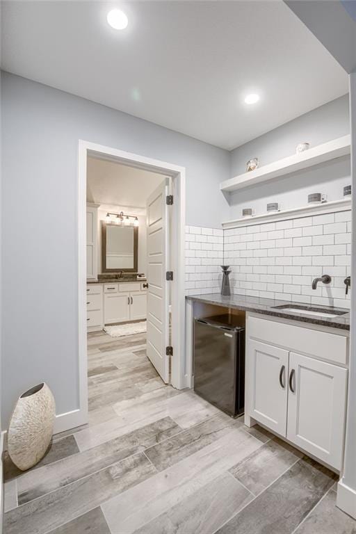 kitchen with sink, white cabinetry, tasteful backsplash, fridge, and light hardwood / wood-style floors