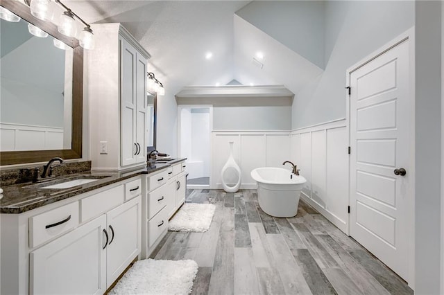 bathroom with a washtub, vanity, hardwood / wood-style floors, and lofted ceiling