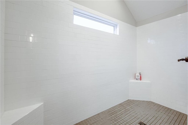 bathroom featuring lofted ceiling, tile patterned flooring, and a tile shower