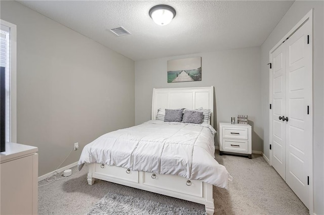 carpeted bedroom with a textured ceiling and a closet