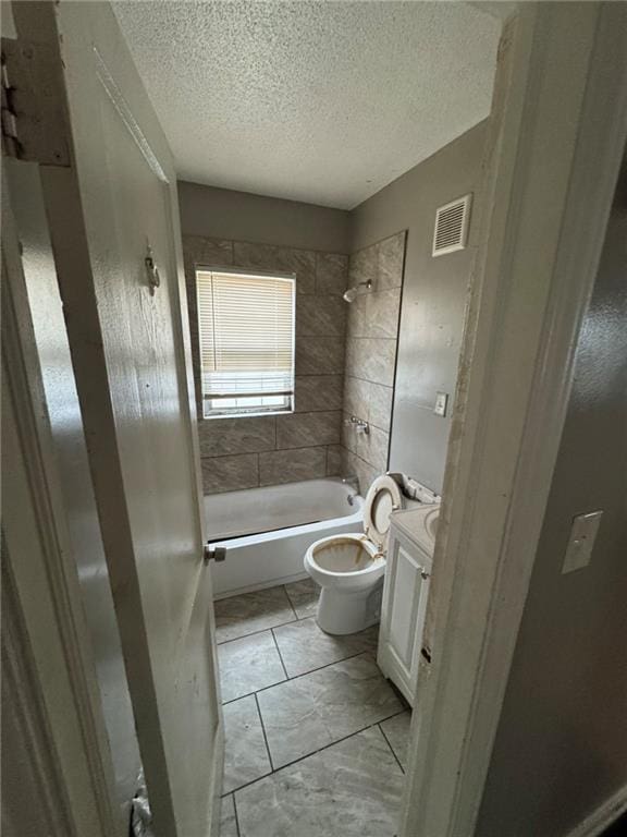 full bathroom featuring vanity, tiled shower / bath, a textured ceiling, and toilet