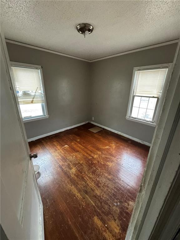 empty room with dark hardwood / wood-style flooring, crown molding, and a textured ceiling