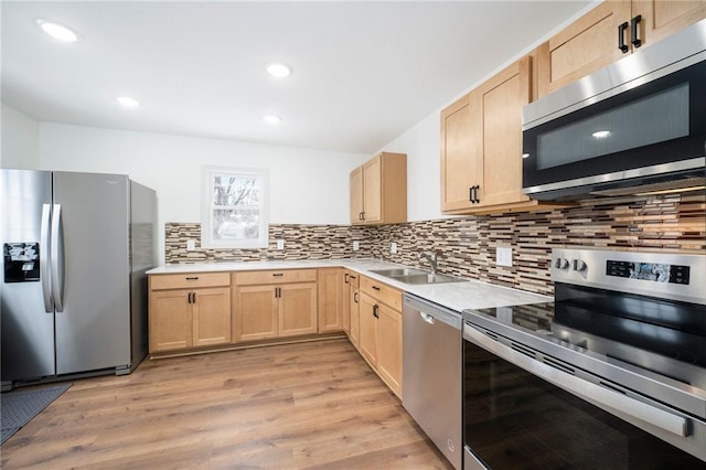 kitchen featuring sink, stainless steel appliances, light brown cabinetry, and light hardwood / wood-style floors