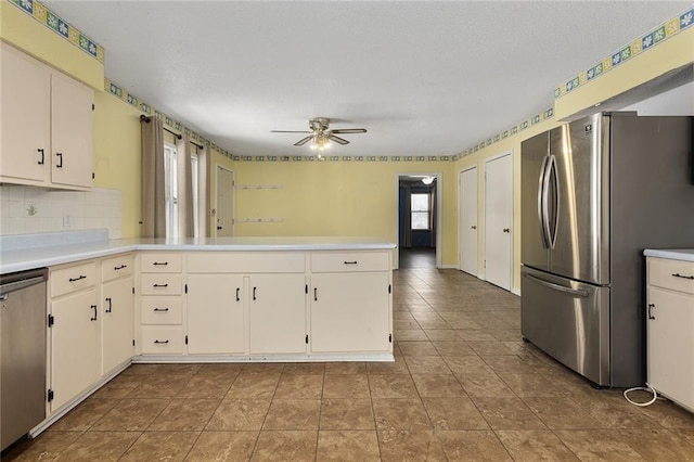 kitchen featuring white cabinetry, appliances with stainless steel finishes, kitchen peninsula, ceiling fan, and backsplash