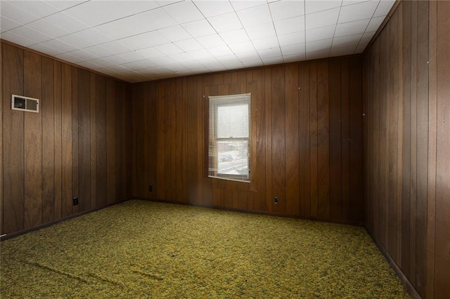 unfurnished room with carpet floors and wood walls