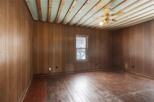 empty room with hardwood / wood-style floors, ceiling fan, and wood walls