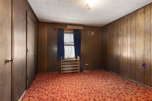 carpeted spare room with wooden walls