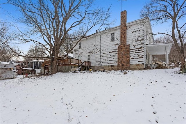 snow covered back of property with a wooden deck