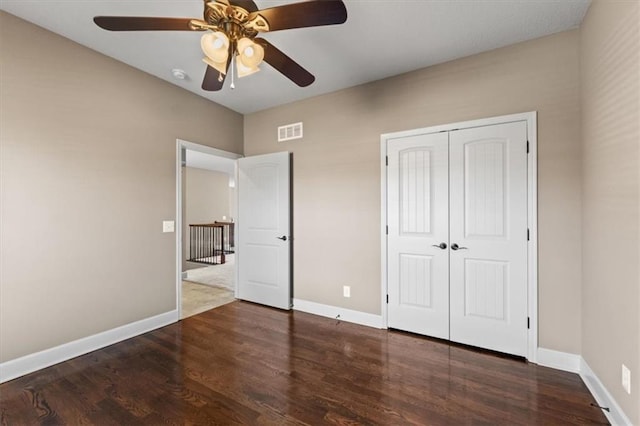 unfurnished bedroom featuring wood finished floors, visible vents, baseboards, ceiling fan, and a closet