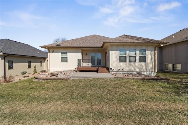 rear view of property featuring a yard and roof with shingles