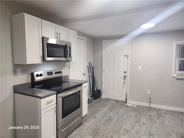 kitchen featuring stainless steel appliances, white cabinets, and light hardwood / wood-style floors