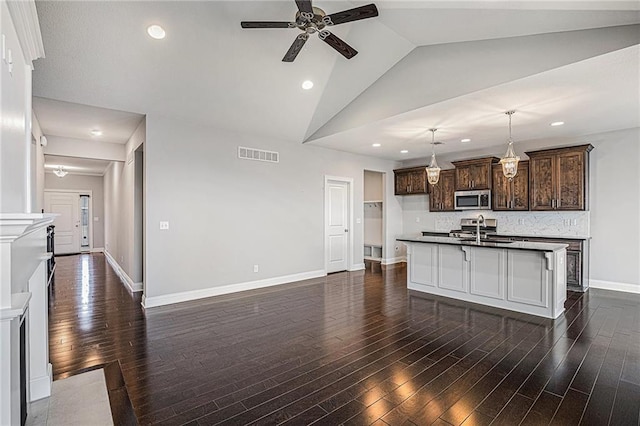 kitchen featuring sink, decorative light fixtures, dark brown cabinets, dark hardwood / wood-style flooring, and an island with sink