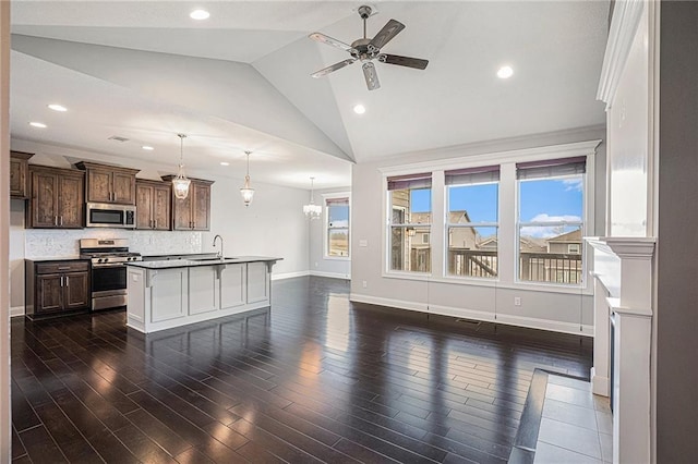 kitchen with appliances with stainless steel finishes, pendant lighting, an island with sink, sink, and dark brown cabinets