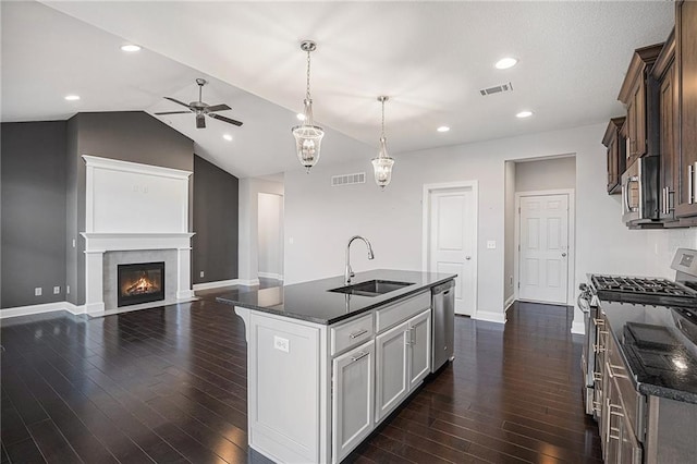 kitchen with sink, hanging light fixtures, dark hardwood / wood-style floors, an island with sink, and stainless steel appliances