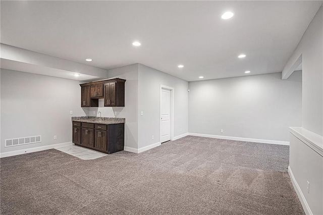 unfurnished living room featuring light carpet and wet bar