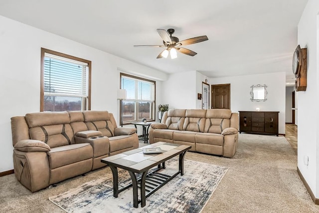 living area with light carpet, ceiling fan, and baseboards