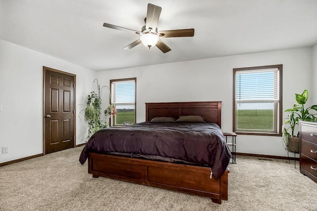 bedroom featuring a ceiling fan, light colored carpet, and baseboards