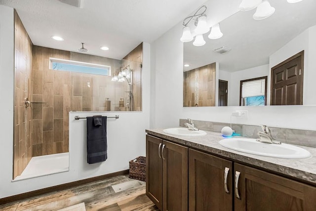 full bath with wood finished floors, visible vents, a sink, and a walk in shower