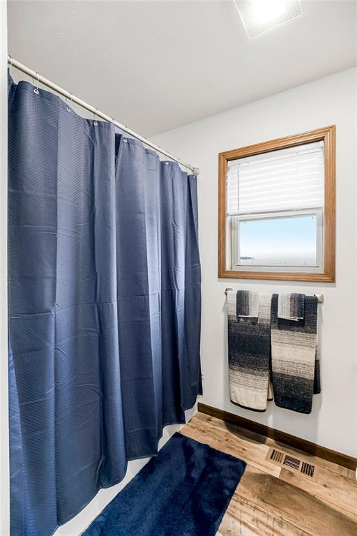 full bath featuring baseboards, visible vents, and wood finished floors