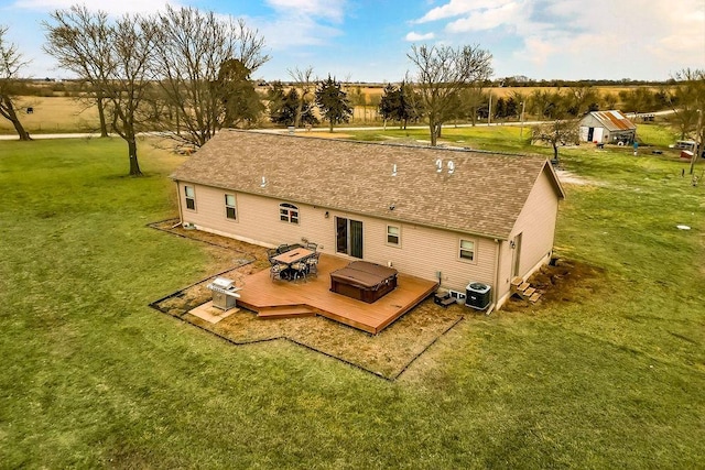 rear view of house with a shingled roof, a deck, central AC, and a yard