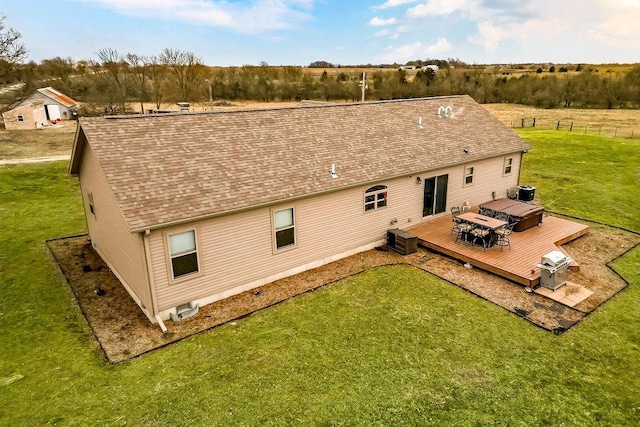 rear view of house featuring a shingled roof, central AC unit, a lawn, outdoor dining area, and a deck