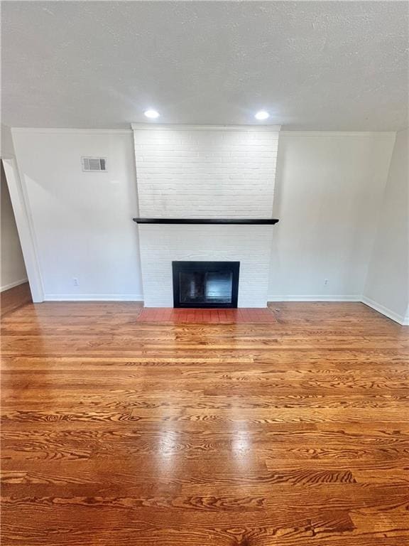 unfurnished living room with hardwood / wood-style flooring, a fireplace, and a textured ceiling