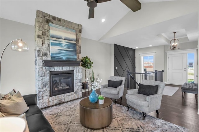 living room featuring ceiling fan with notable chandelier, a fireplace, hardwood / wood-style floors, and vaulted ceiling with beams