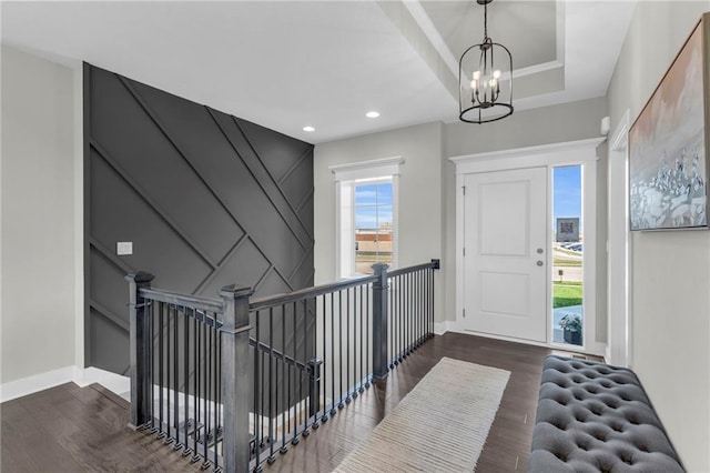 entrance foyer with a tray ceiling, dark hardwood / wood-style floors, and a notable chandelier