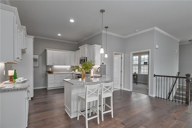 kitchen with pendant lighting, dark hardwood / wood-style flooring, sink, and white cabinets