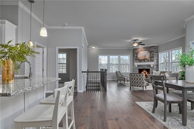 dining room featuring dark hardwood / wood-style floors, a stone fireplace, sink, and a wealth of natural light