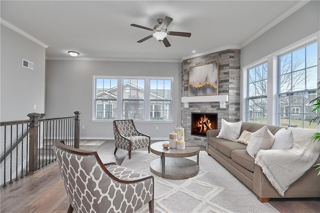 living room featuring ornamental molding, plenty of natural light, hardwood / wood-style floors, and a stone fireplace