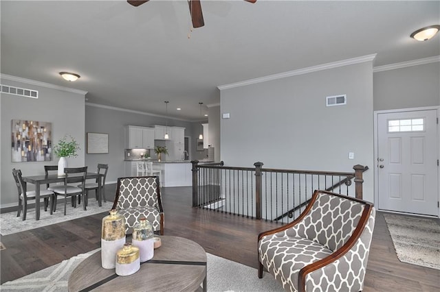 living room with crown molding, dark wood-type flooring, and ceiling fan