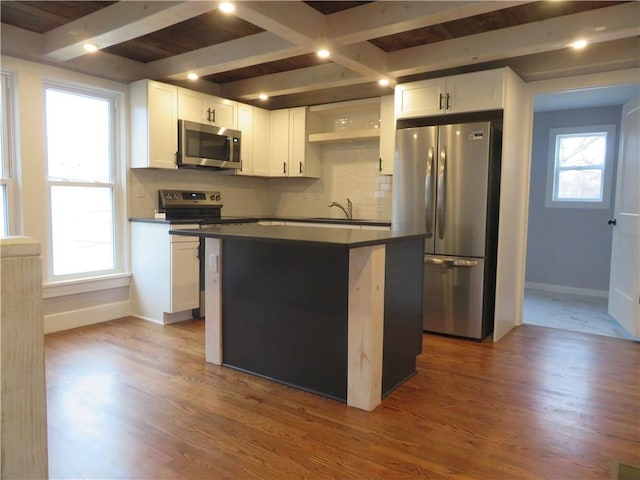 kitchen with beam ceiling, a center island, white cabinets, and appliances with stainless steel finishes