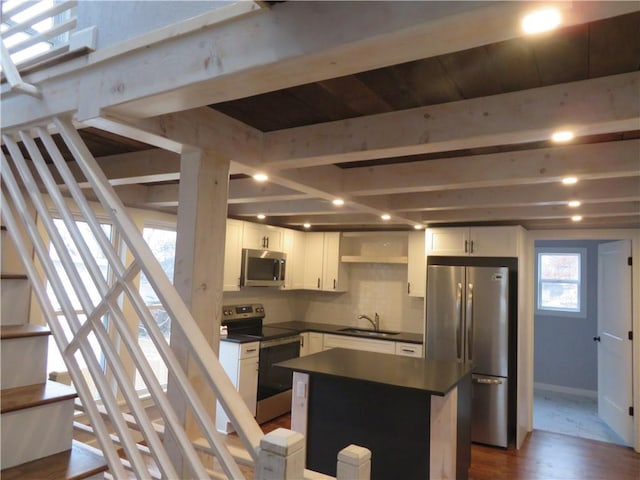 kitchen with sink, a kitchen island, stainless steel appliances, decorative backsplash, and white cabinets