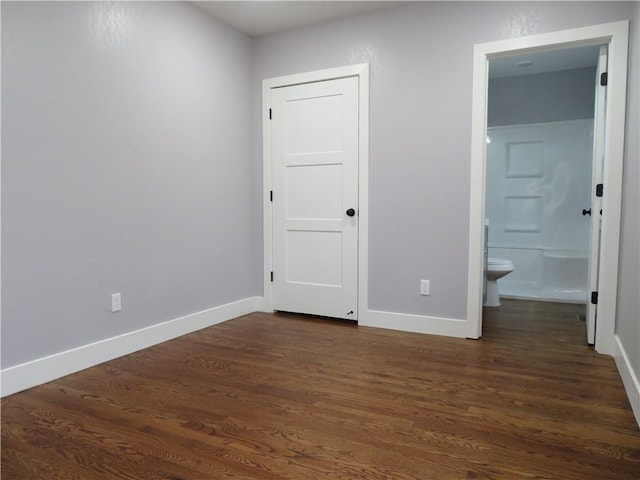 unfurnished bedroom featuring ensuite bathroom and dark hardwood / wood-style floors