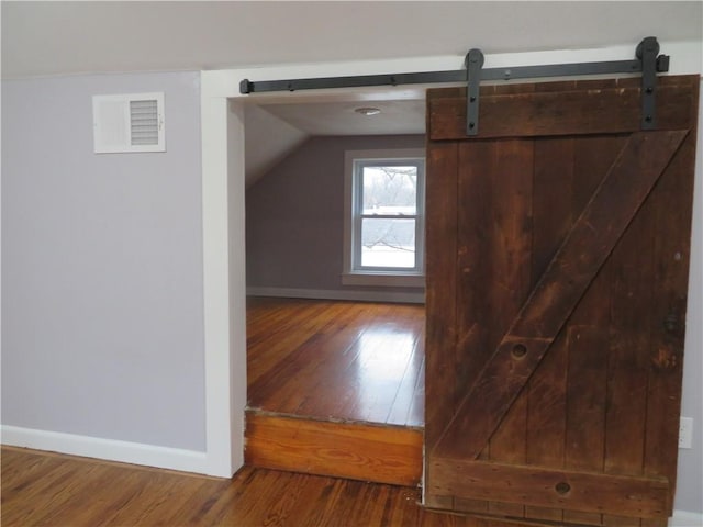 bonus room with a barn door, hardwood / wood-style floors, and lofted ceiling