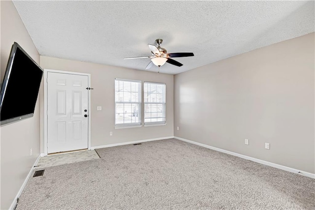 unfurnished room featuring a textured ceiling, visible vents, baseboards, a ceiling fan, and carpet