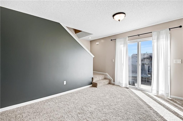 unfurnished room with stairs, a textured ceiling, carpet, and baseboards